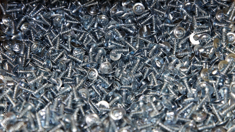 New short gray self tappers screws with cross heads. Zinc galvanized construction fasteners. Industrial texture for the background. New short gray self tappers screws with cross heads. Zinc galvanized construction fasteners. Industrial texture for the background.