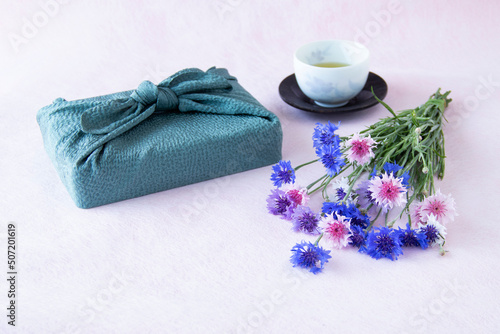 日本茶とヤグルマギクの花束と風呂敷包みのデザイン（ペールピンクの背景）	