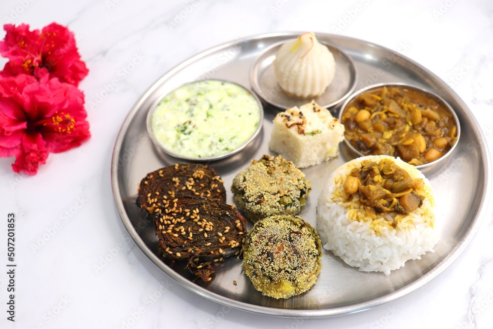 Indian vegetarian lunch or dinner Thali includes beans sabzi, dal rice, Alu Vadi, dhokla, veg cutlet, raita, and ukdiche modak. Indian food is served on a plate or thali. Ganesh Jayanti Food. Copy Indian vegetarian lunch or dinner Thali includes beans sabzi, dal rice, Alu Vadi, dhokla, veg cutlet, raita, and ukdiche modak. Indian food is served on a plate or thali. Ganesh Jayanti Food. Copy