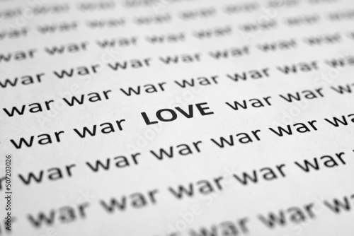Close-up of word Love and many words War on white sheet of paper. Selective focus, macro photo