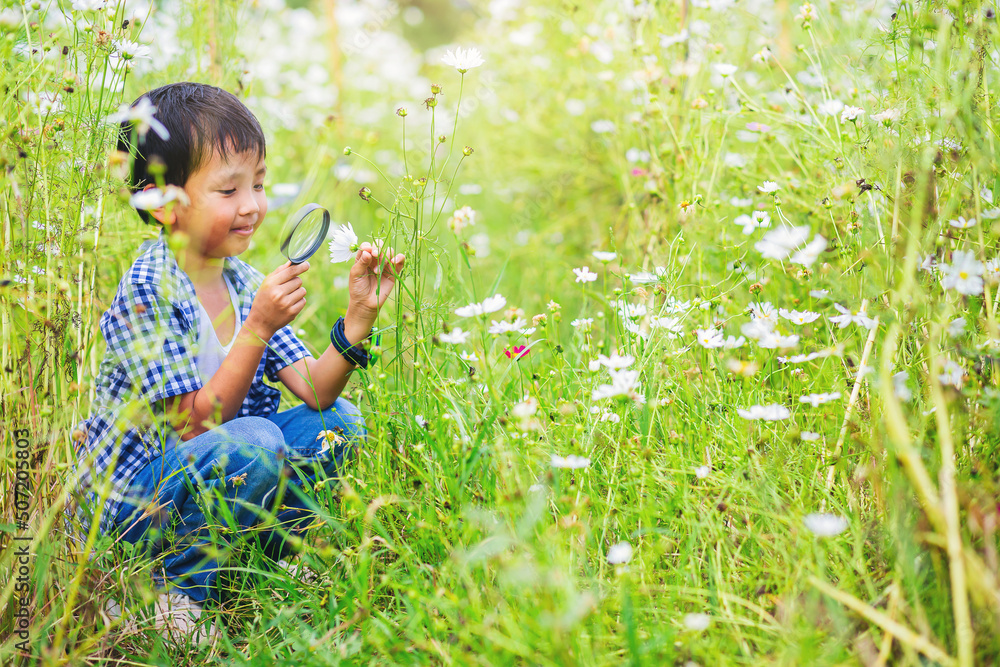 Happiness boy with magnifying glass explorer and learning the nature, flower garden backyard Happiness boy with magnifying glass explorer and learning the nature, flower garden backyard