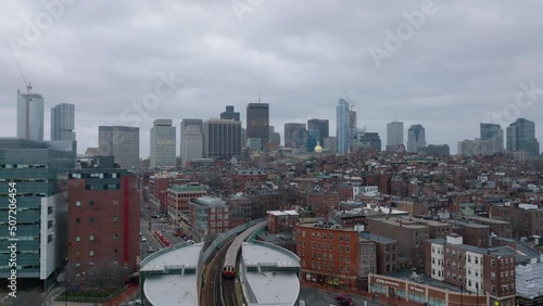 Aerial ascending footage of subway leaving overground station. Revealing cityscape with high rise buildings in background. Boston, USA photo