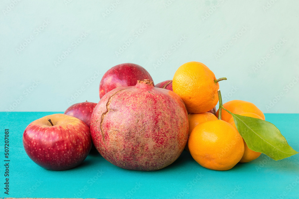Pomegranates, apples, and tangerines on a turquoise background. Ripe fruits. Pomegranates, apples, and tangerines on a turquoise background. Ripe fruits.