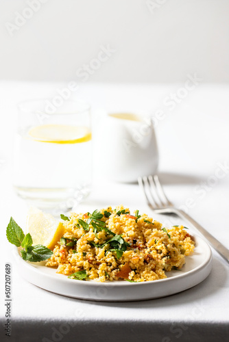 Restaurant table setting  for menu cart. Tabule salad made with bulgur, chopped parsley, tomatoes, mint, onion and seasoned with olive oil and lemon juice served with glass of water. photo