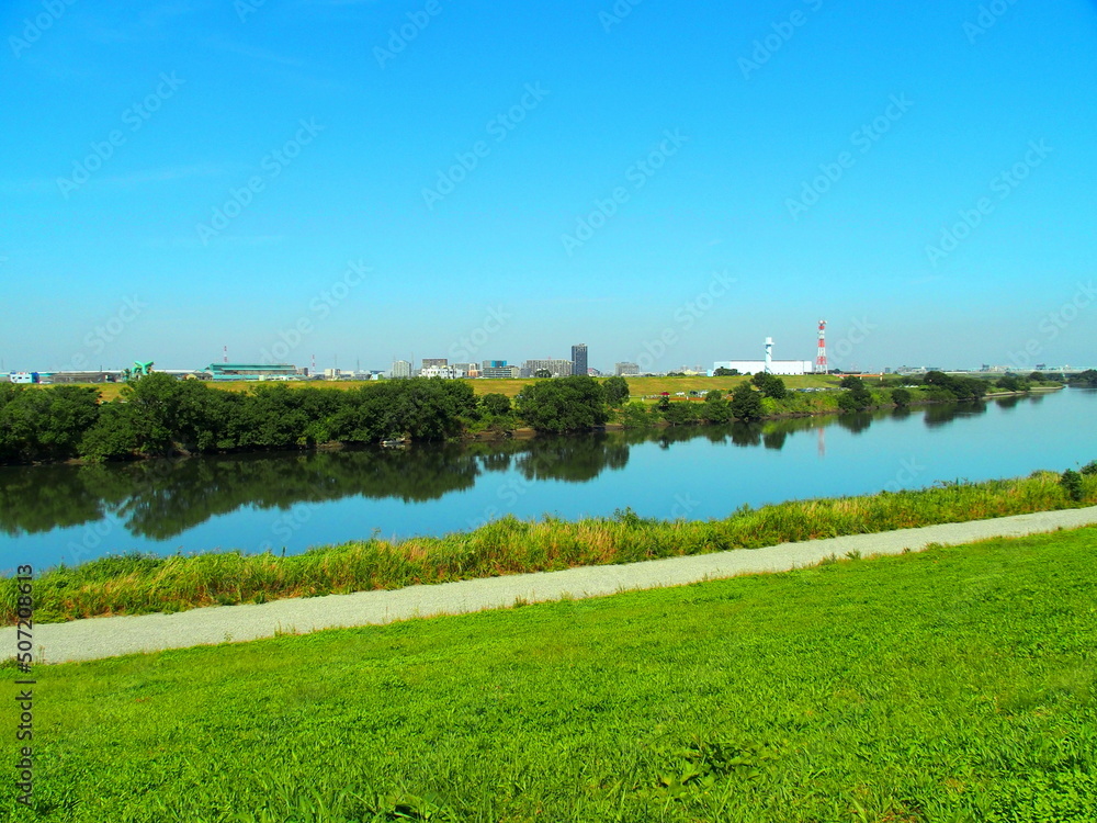 Obraz premium 土手の上から見る秋の青空を映す江戸川風景