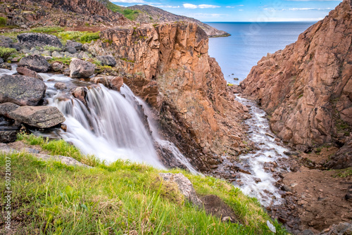 Summer polar landscape with waterfall in Teriberka. Kola Peninsula of the Barents Sea. The nature of the north of Russia