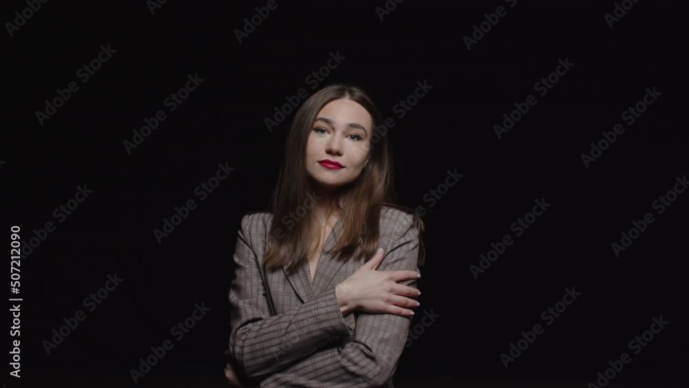A beautiful young brunette in a jacket looks into the camera posing on a black background. A beautiful young brunette in a jacket looks into the camera posing on a black background.