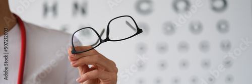 Woman doctor ophthalmologist shows glasses, close-up, blurry