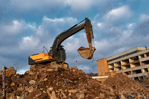 Building excavator on concrete pieces at demolition site