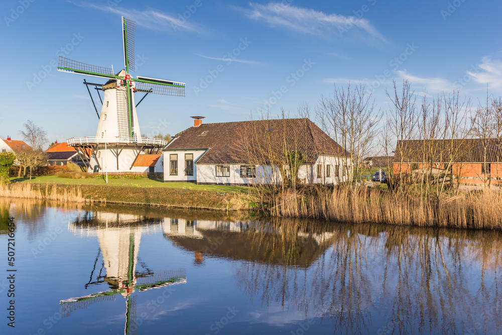 Historic windmill reflecting in the Damsterdiep river in Ten Boer, Netherlands
