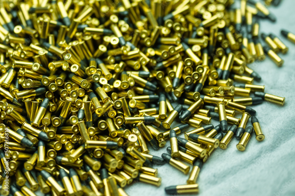 Heap of black and golden small-caliber bullets on table Heap of black and golden small-caliber bullets on table