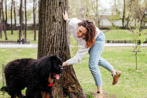 Smiling woman playing with tibetan mastiff dog outdoors. Girl and dog in park