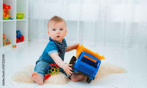 Fotografie, Obraz cute baby is sitting on the floor of the house, playing with colorful educationa