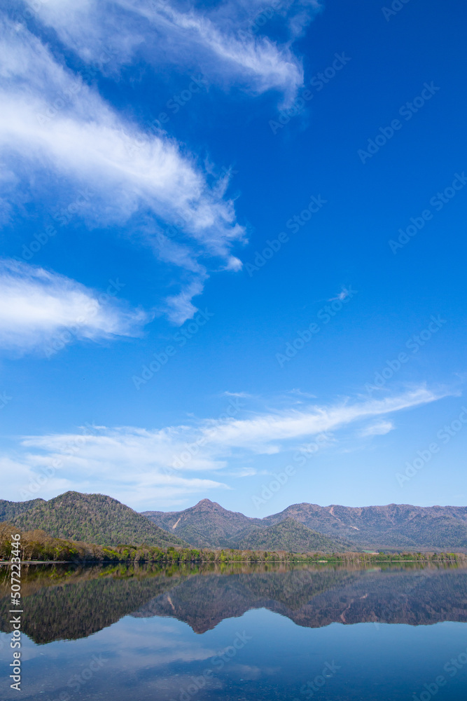 Obraz premium 青空の下、山々を湖面に映す湖。