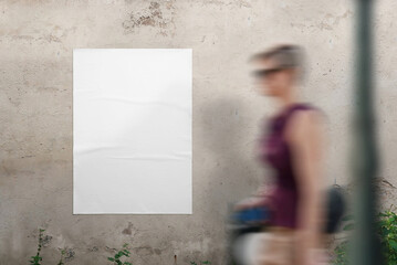Blank poster mockup on the wall for design presentation. A young woman walks past