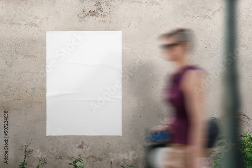 Blank poster mockup on the wall for design presentation. A young woman walks past