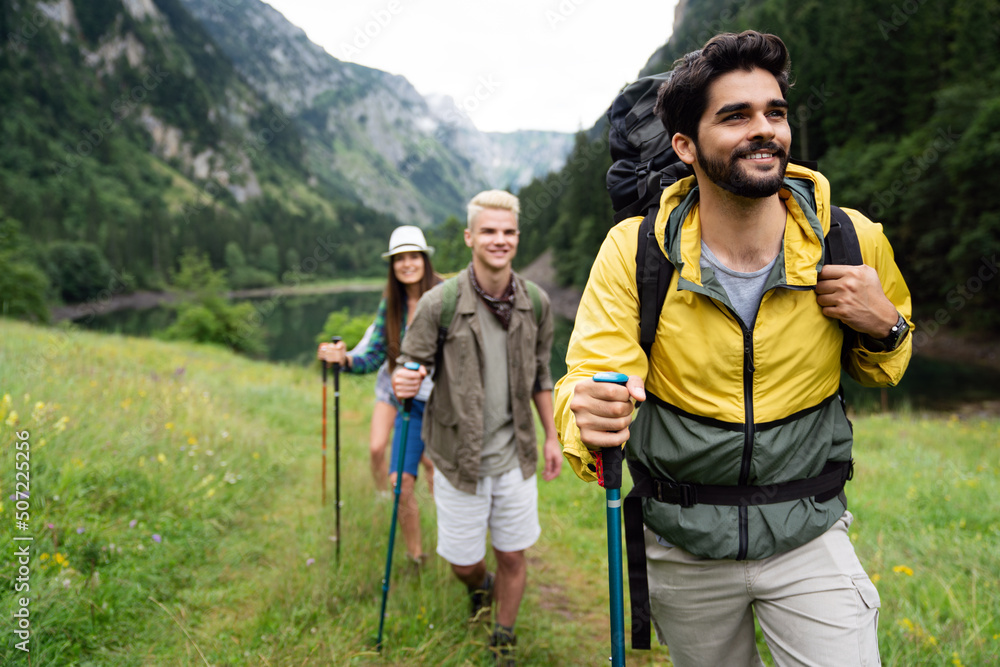Group of smiling friends hiking with backpacks outdoors. Travel, tourism, hike and people concept.