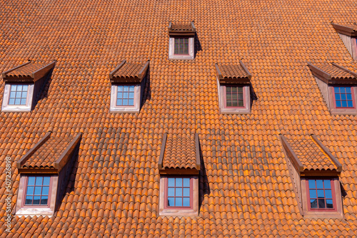 Many small windows on a red roof covered with tiles in the old town of Gdansk © k_samurkas