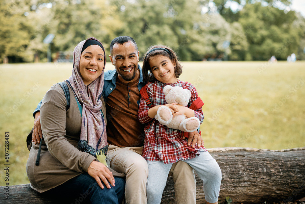 Portrait of happy Muslim family in nature and looking at camera.