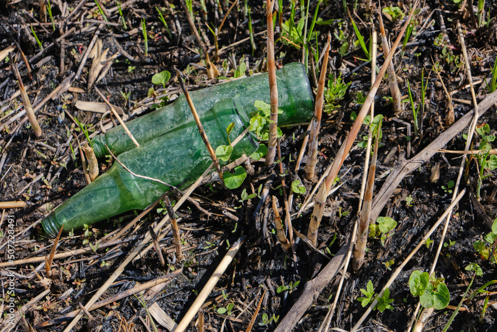 Fototapeta premium Garbage and glass bottles on the scorched earth after the fire.