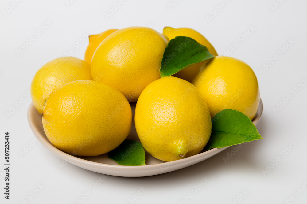 Fresh cutted lemon and whole lemons over round plate on colored background. Food and drink ingredients preparing. healthy eating theme top view vith copy space Fresh cutted lemon and whole lemons over round plate on colored background. Food and drink ingredients preparing. healthy eating theme top view vith copy space