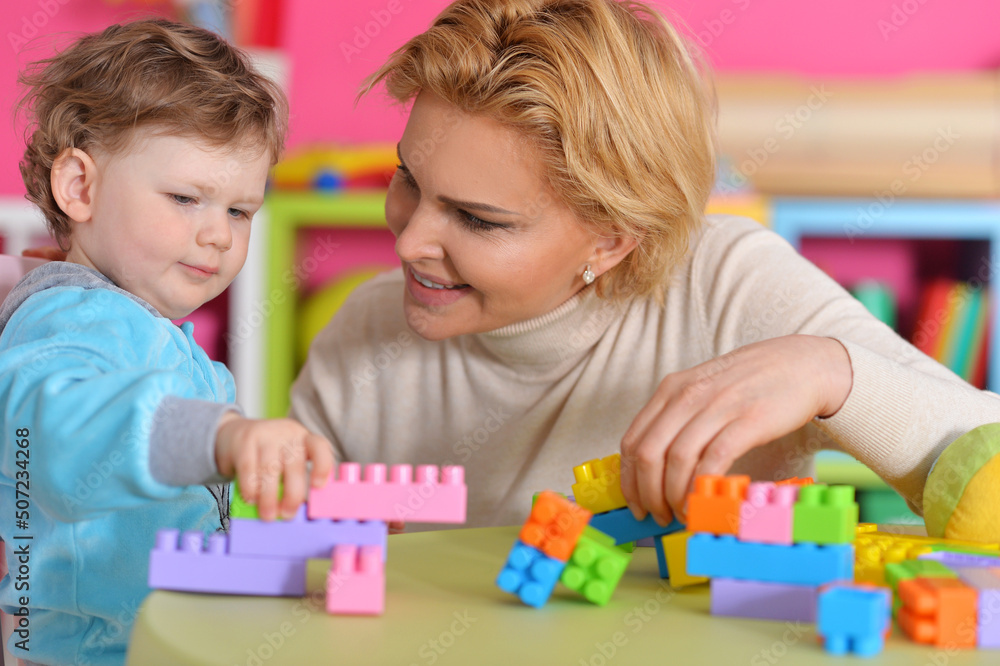 Mom plays with her little daughter sitting at the table Mom plays with her little daughter sitting at the table