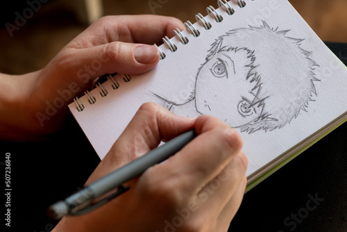 girl draws a human face in anime style with a pencil