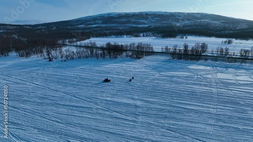 Beautiful aerial video of unrecognizable people on snowmobiles pull unrecognizable children on small snow sledges. Sunny winter day in Swedish Mountains. Joesjo, Sweden photo