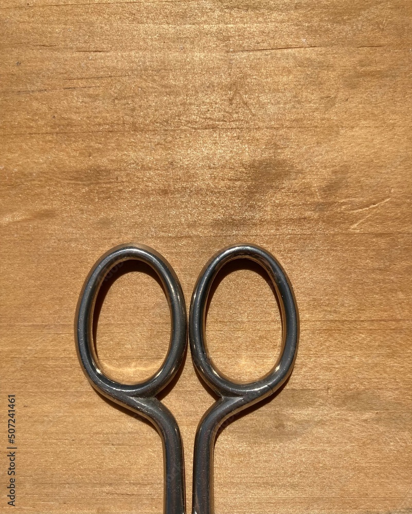 handle of metal scissors on a wooden surface handle of metal scissors on a wooden surface