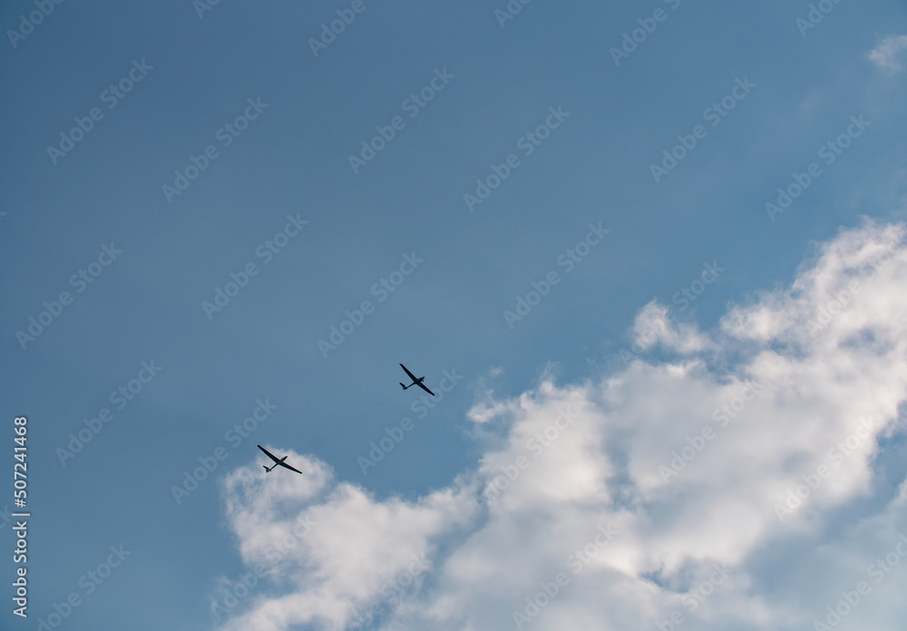 Small plane pulls glider to the sky to start the gliding flight. Thy sky is blue with some clouds. Small plane pulls glider to the sky to start the gliding flight. Thy sky is blue with some clouds.
