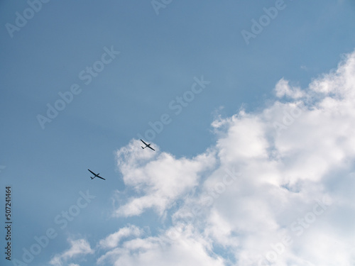 Glider near clouds. Small plane pulls glider to the sky to start the gliding flight. Thy sky is blue with some clouds. 