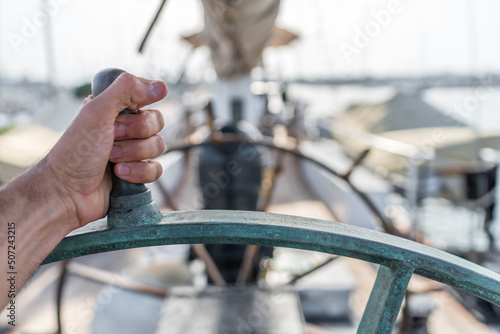 Left hand holding ship wheel with blurred background