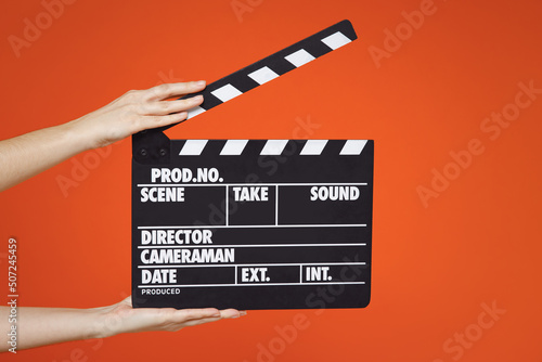 Foto Close up female holding in hand classic director clear empty black film making clapperboard isolated on yellow orange background
