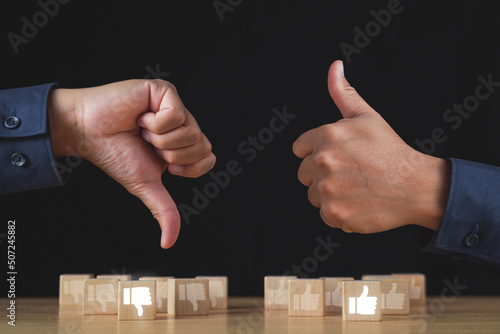 Sign of thumbs up and thumbs down to show the like and unlike feeling. Hands and wood blocks isolated on black background. Evaluation and satisfaction concept