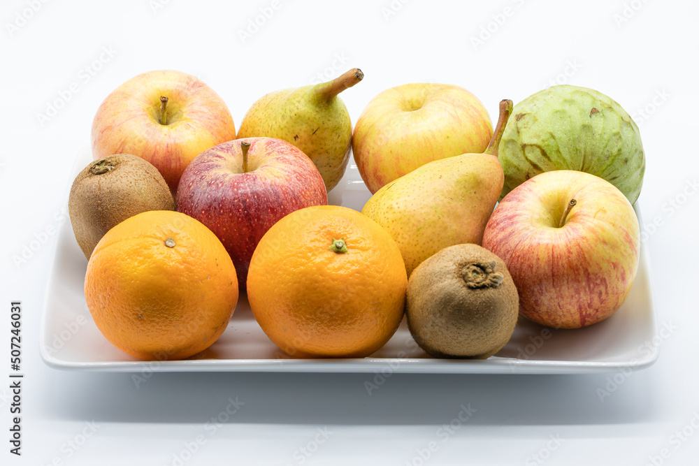 Variety of fresh fruit in a ceramic tray isolated on a white background