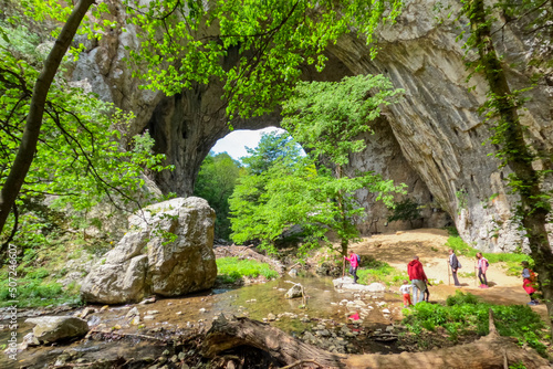 Family nature hiking adventure. Mother with grandma and daughter, standing by a clear mountain creek near imposing natural stone arches, Vratna River Canyon, eastern Serbia photo