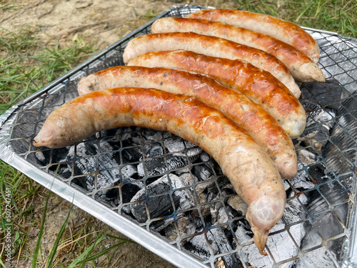 Bratwürste auf einem Einweggrill beim Camping photo