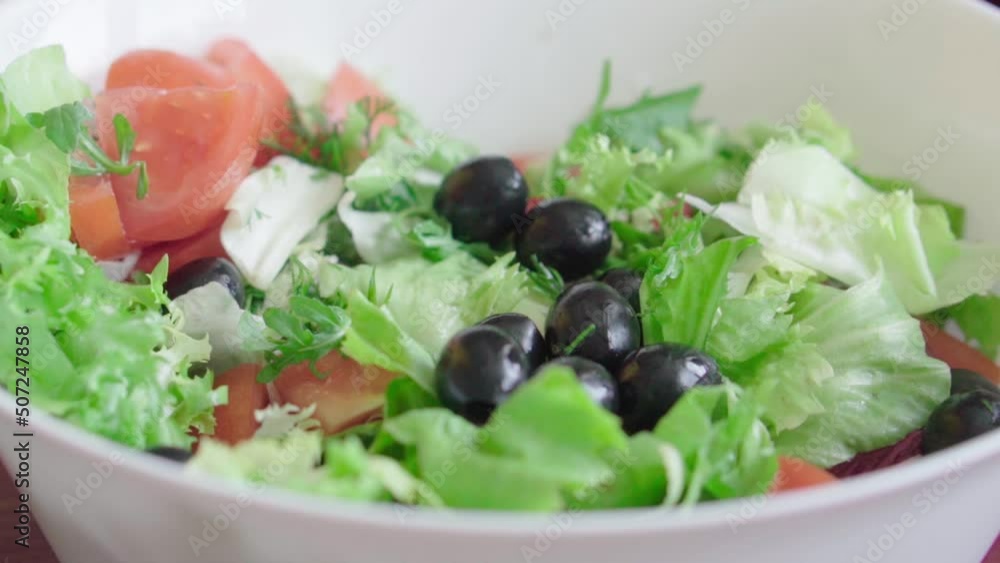 Cooking healthy food in the kitchen. Fresh vegetable salad. Vegetarian diet. Close up of healthy lunch with radishes, tomatoes, lettuce, fragrant herbs and olives. Woman cuts and mixes salad. Cooking healthy food in the kitchen. Fresh vegetable salad. Vegetarian diet. Close up of healthy lunch with radishes, tomatoes, lettuce, fragrant herbs and olives. Woman cuts and mixes salad.