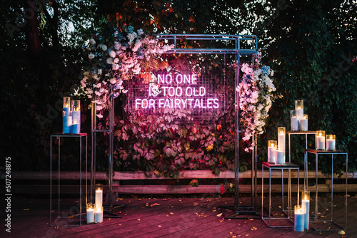 Fotografie No one is too old for fairytales - neon sign on a wall at an outdoor wedding party