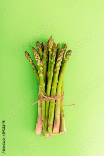 Green asparagus on light green background. Healthy food, top view, flat lay