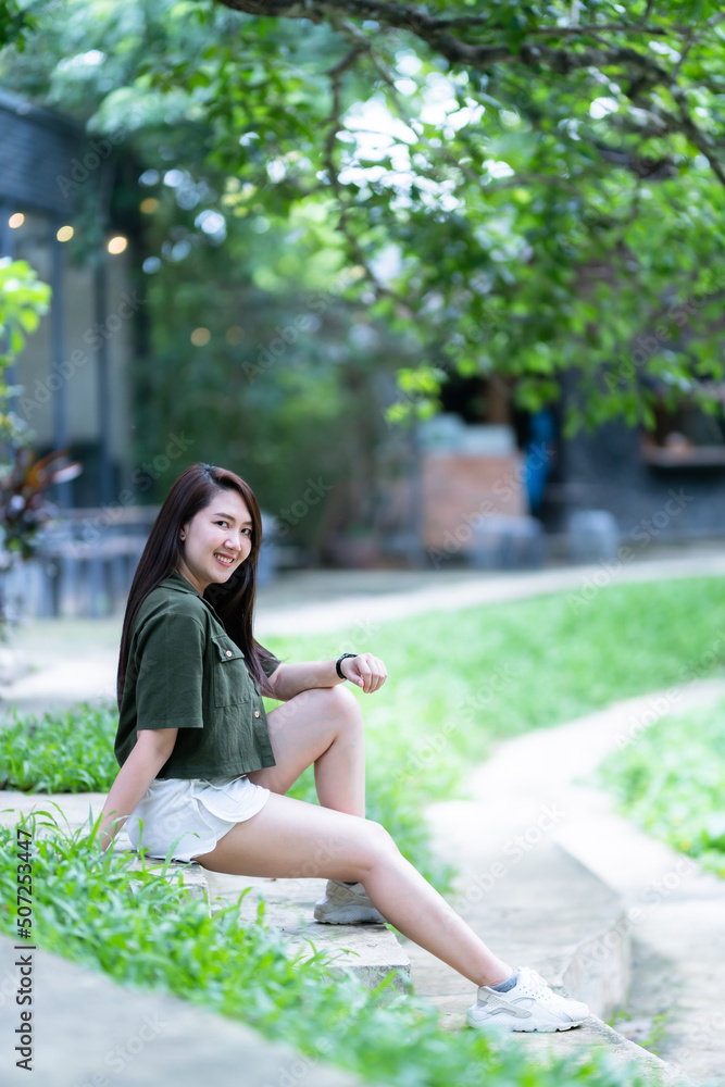 a portrait of beautiful happy asian woman traveler wearing brownish green dress stylish hipster Summer sunny lifestyle on the street outdoors at sunny summer day in park background