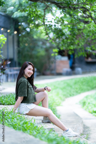 Obraz na płótnie a portrait of beautiful happy asian woman traveler wearing brownish green dress stylish hipster Summer sunny lifestyle on the street outdoors at sunny summer day in park background w salonie