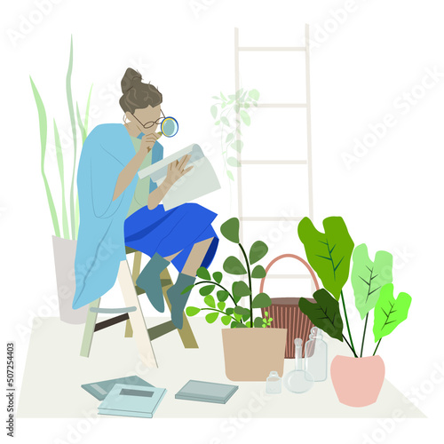 A botanist woman sits on a stepladder among plants and looks through a magnifying glass at a botanical magazine