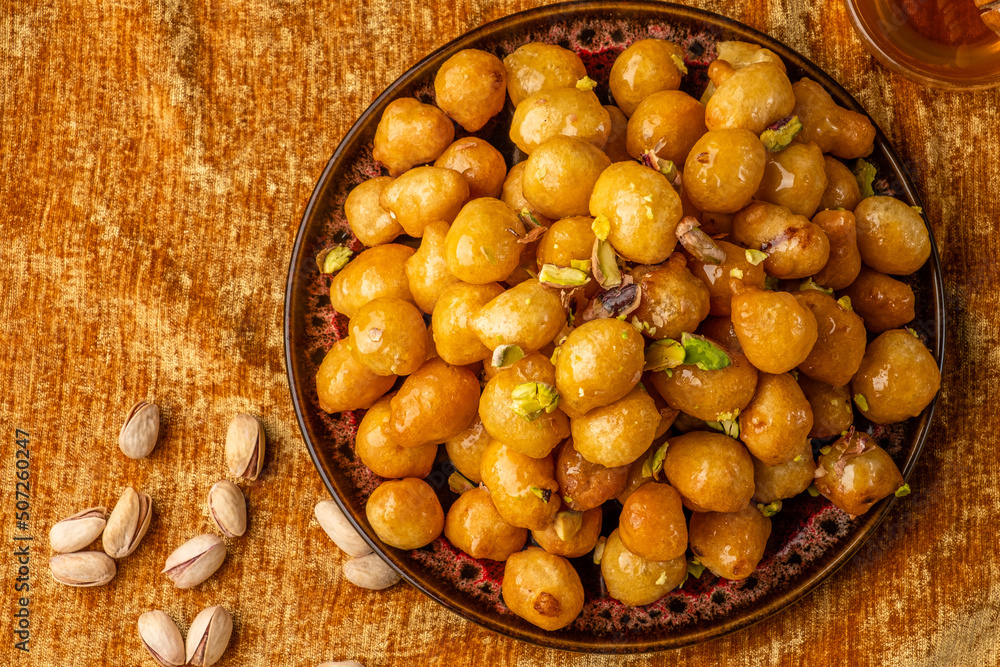 Lokma on a golden fabric background, top view. Sweet Arabic dessert traditional Lokma on a golden fabric background, top view. Sweet Arabic dessert traditional