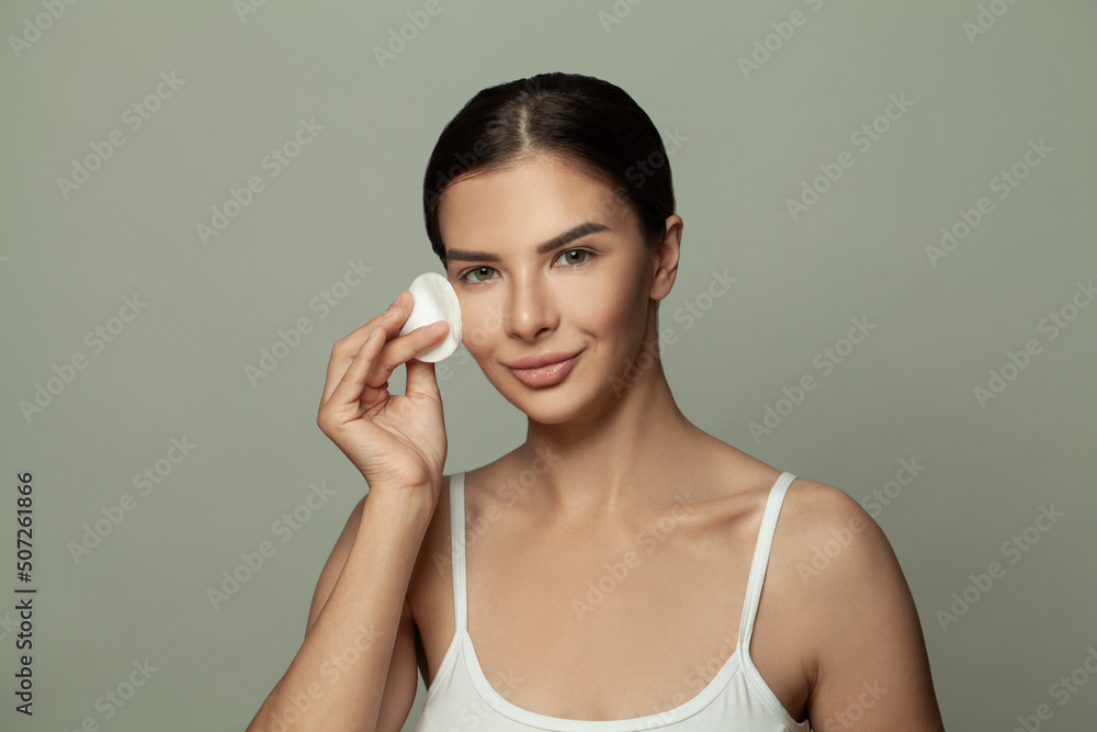 Face Skin Care. Beautiful Woman Removing Makeup With Cotton Pad on Light Green Background Face Skin Care. Beautiful Woman Removing Makeup With Cotton Pad on Light Green Background