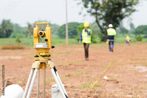 A team of survey engineers working with a theodolite at a commercial building construction site.