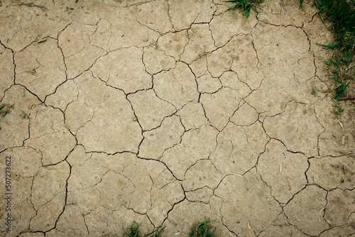 Ground texture with cracks and grass, land without water, top view