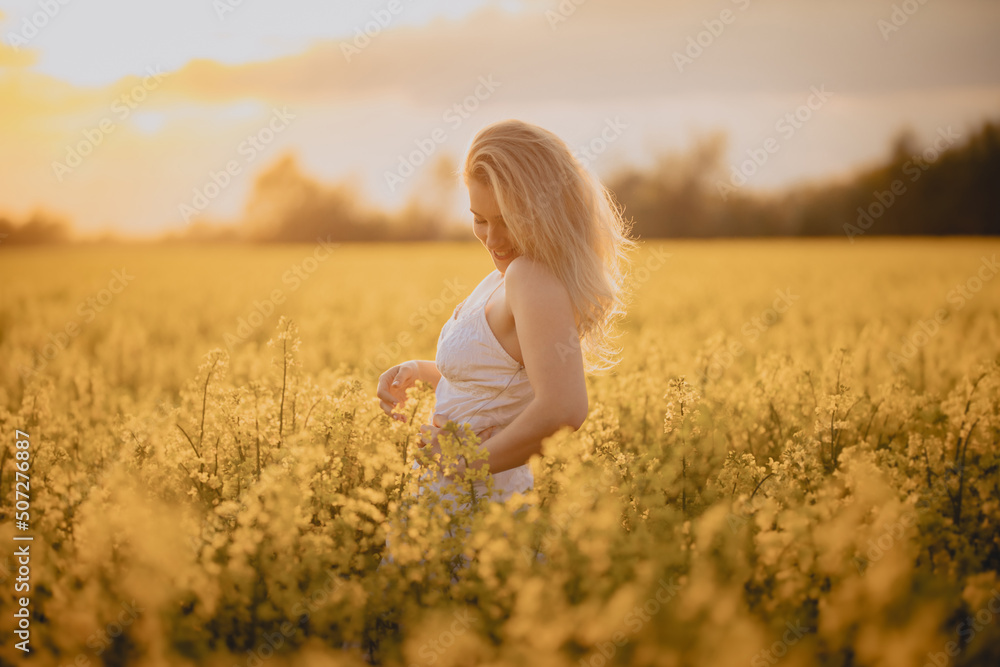 Uśmiechnięta dziewczyna w białej sukience na polu żółtych kwiatów - obrazy, fototapety, plakaty 