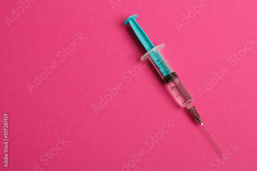 Medical syringe on a pink background. A syringe for injection. The concept of health and beauty