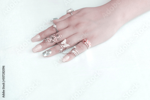 Young woman's hands with multiple bracelets and fingers with many rings on white background. Beautiful Many multicolored rings in a girl's hand.